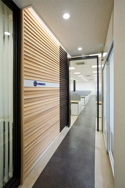 SHIMADZU LIMITED/【Entrance area】The boundary with the office is expressed with ornamental walls made of cedar grown in the prefecture