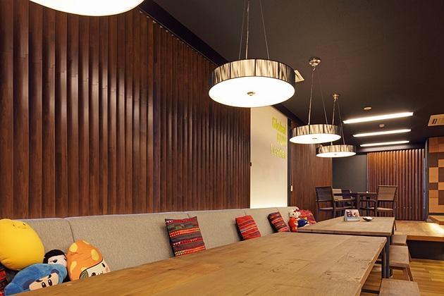 Nexon Co., Ltd./【Sofa area】Style consistency is provided by the use of black for ceilings and wood louvers for windows.