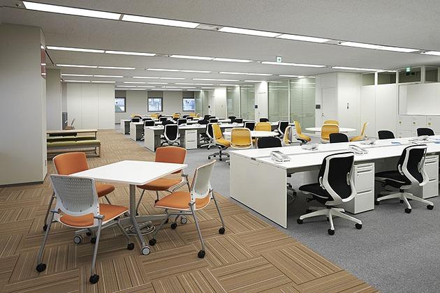 SGS Japan Inc./【Collaboration area】Meeting tables and family-restaurant-style benches are located next to windows with a scenic view.